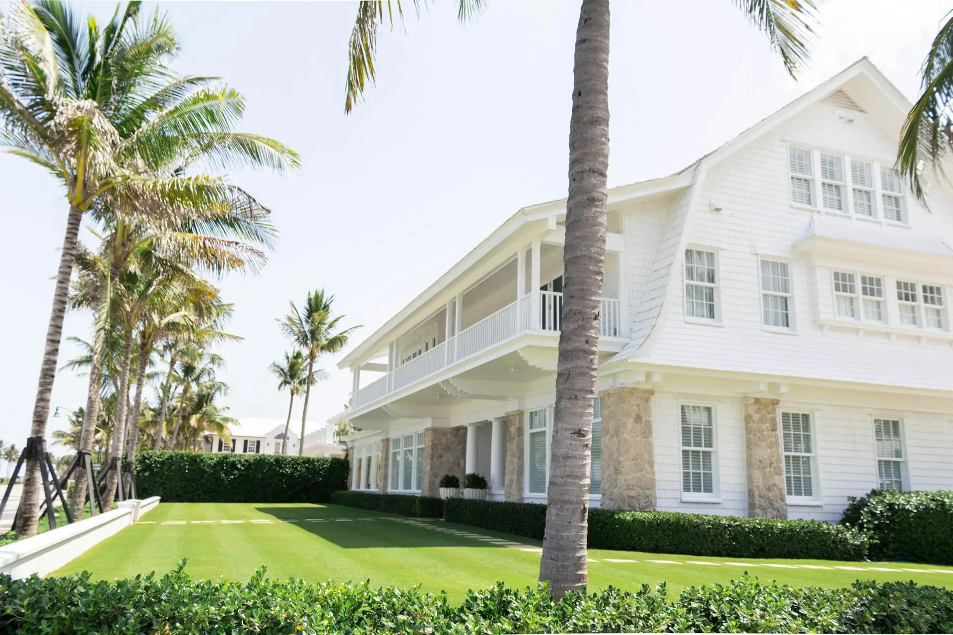 White two-story home framed by palm trees