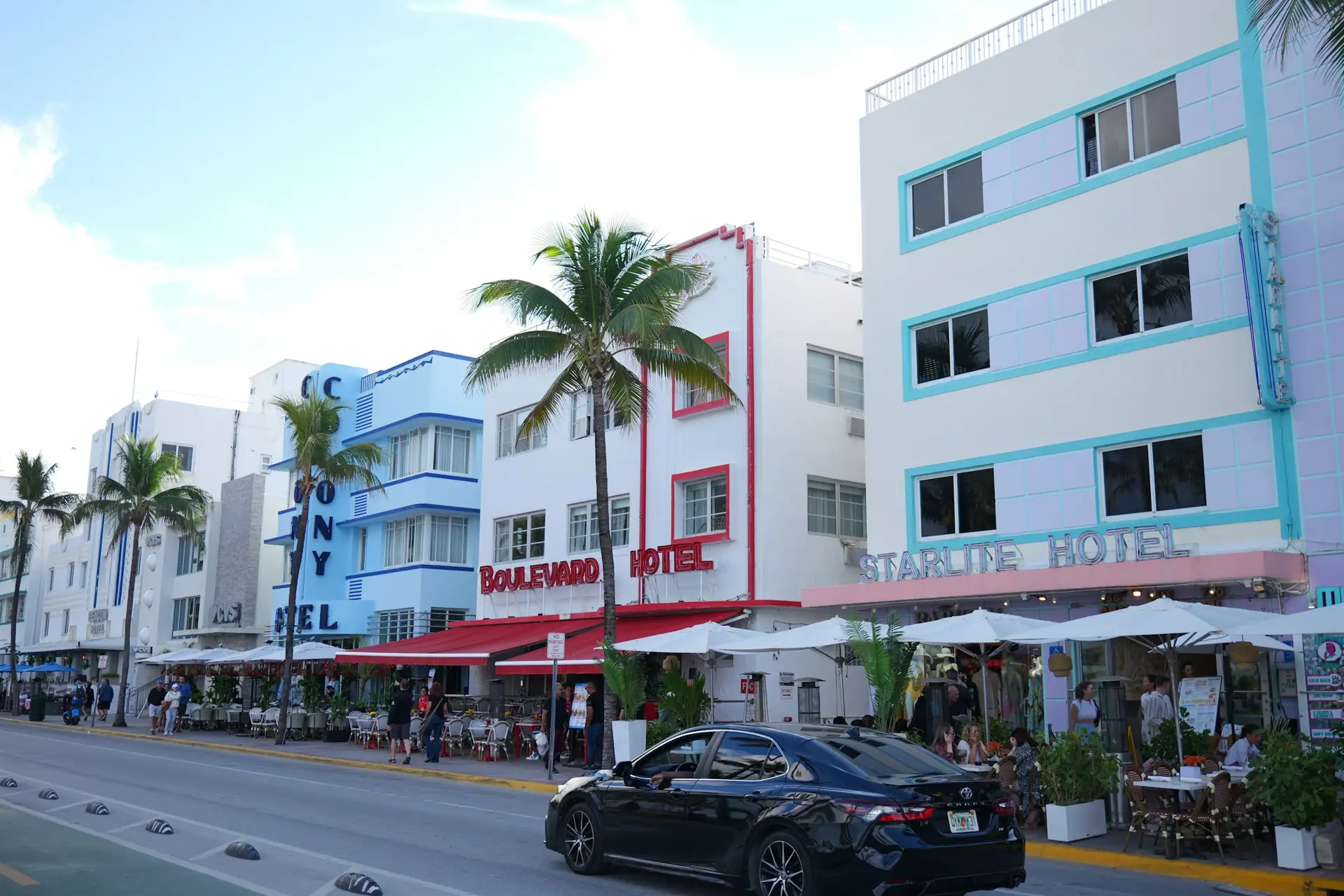 Pastel Art Deco hotels and palm trees along a beachfront street